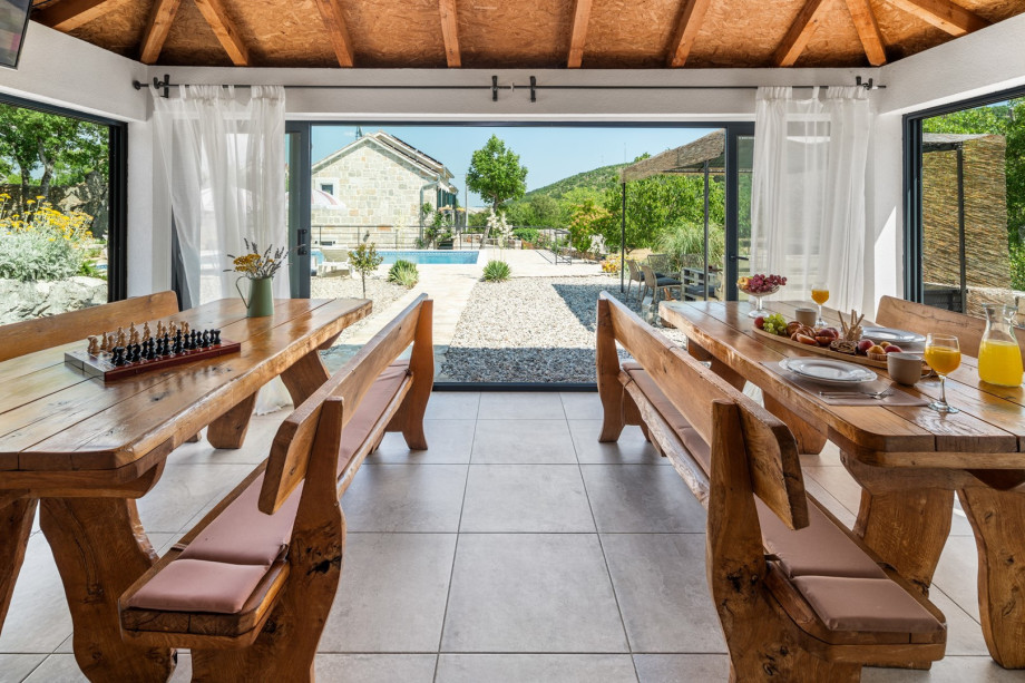 A fully equipped summer kitchen with traditional barbecue area, dining tables, a TV and a separate toilet.