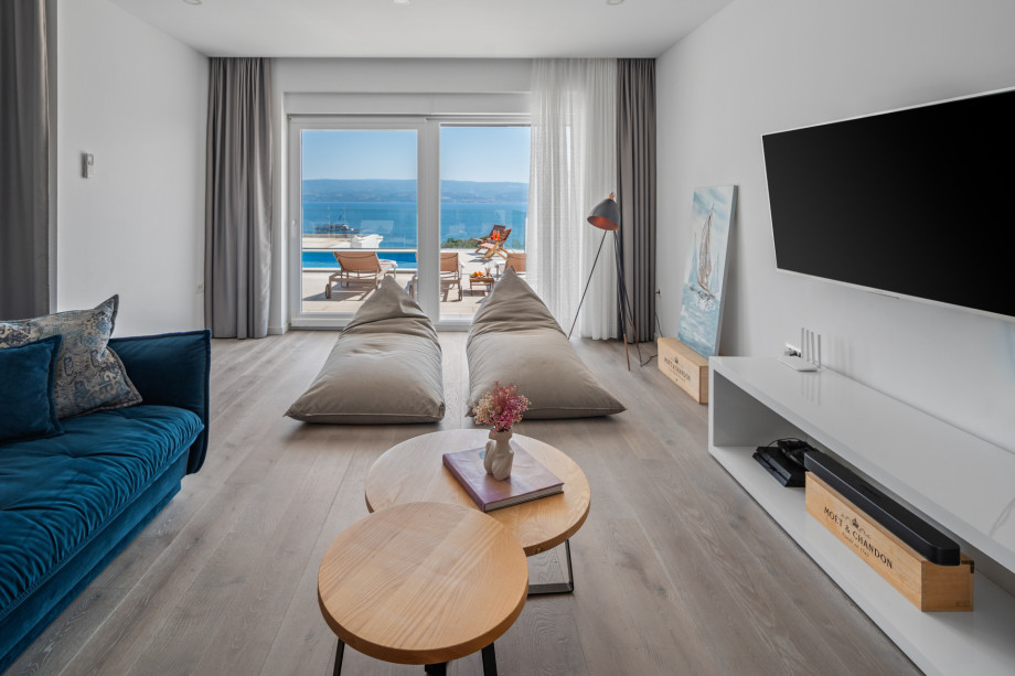 A flat-screen TV, PlayStation 4, A/C, and a glass doors toward the pool