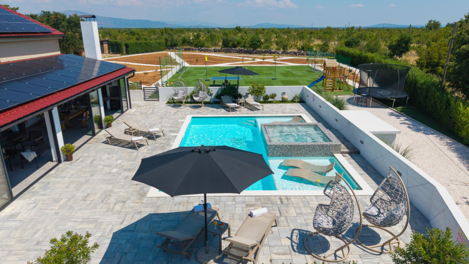 Heated pool with Whirlpool and deck chairs in shallow area with natural surroundings