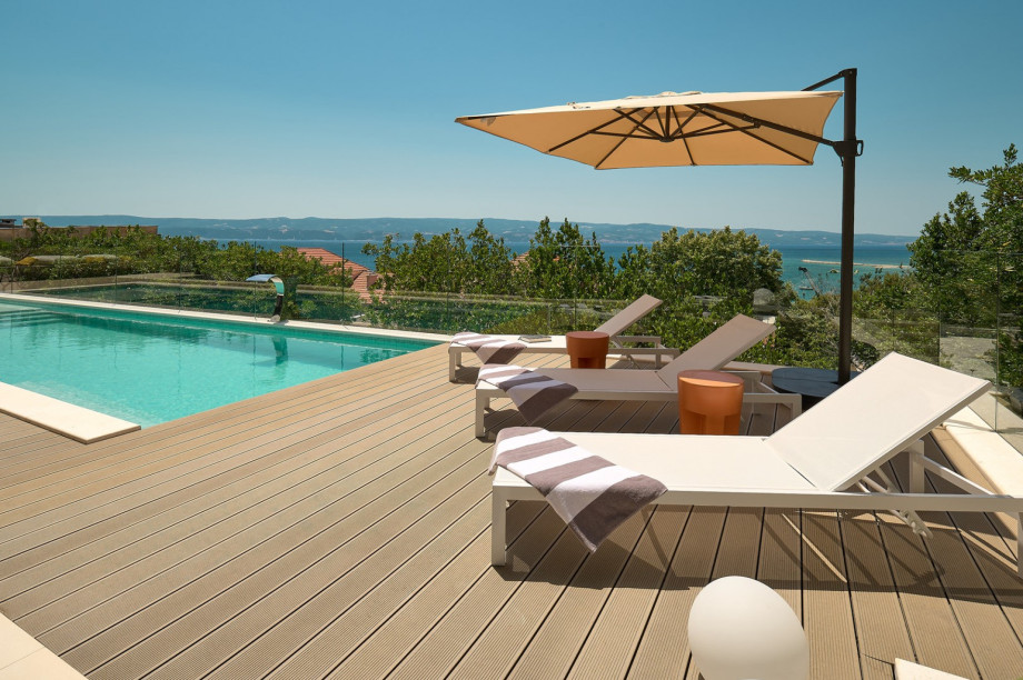 Ein Sonnendeck mit 4 Liegestühlen und einer eingebauten Sonnendeckbank mit Kissen, einer Außendusche