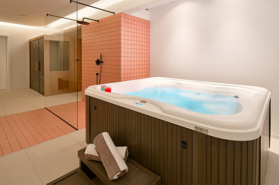 Ein Wellnessraum mit finnischer Sauna, Whirlpool im Innenbereich, Dusche und Toilette