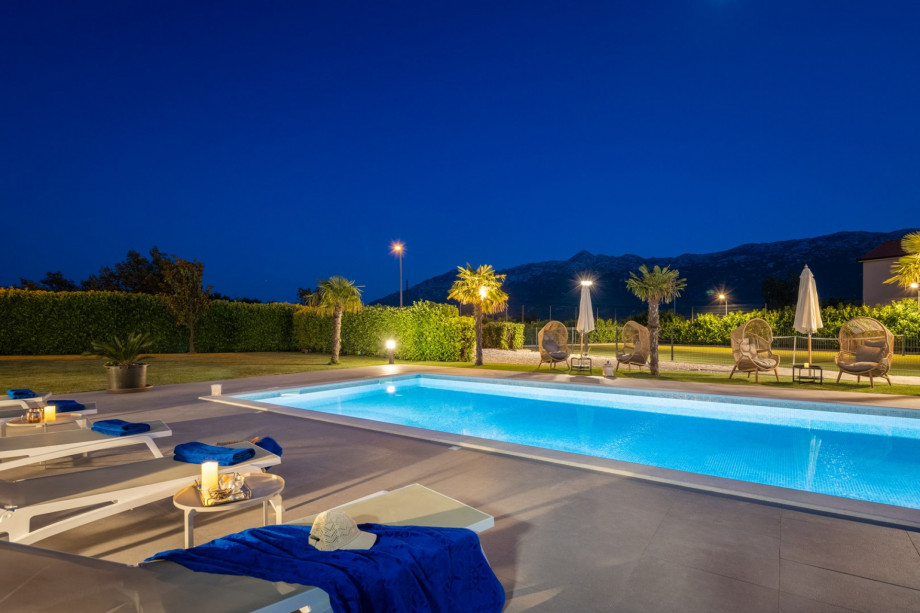 a private and heated, 5m x 10m swimming pool with a spacious sun deck area at night