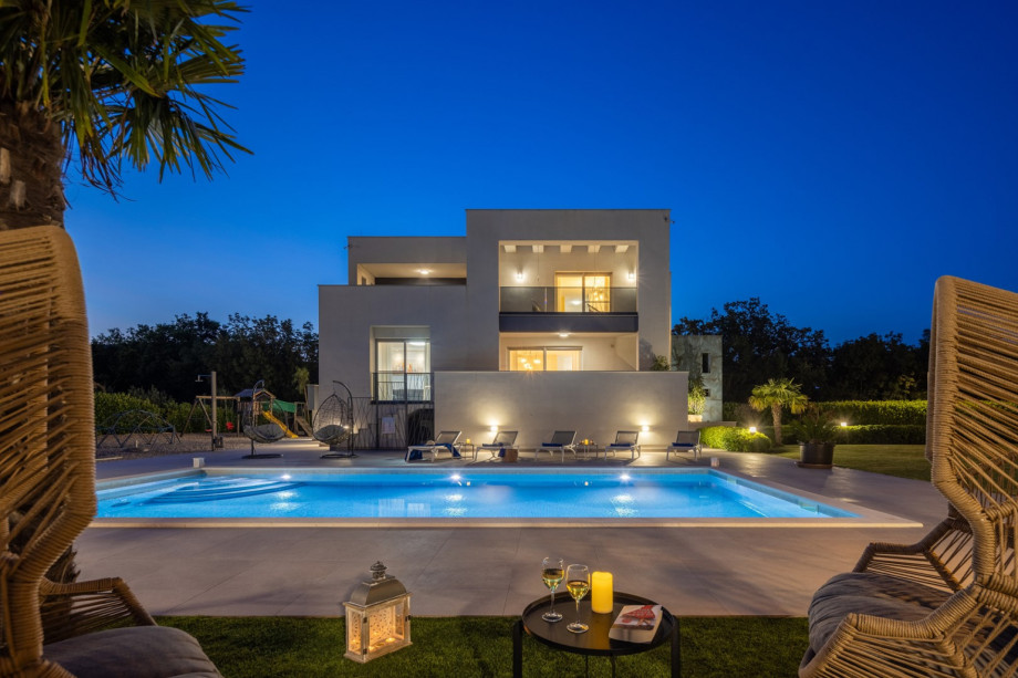 a private and heated, 5m x 10m swimming pool with a spacious sun deck area at night