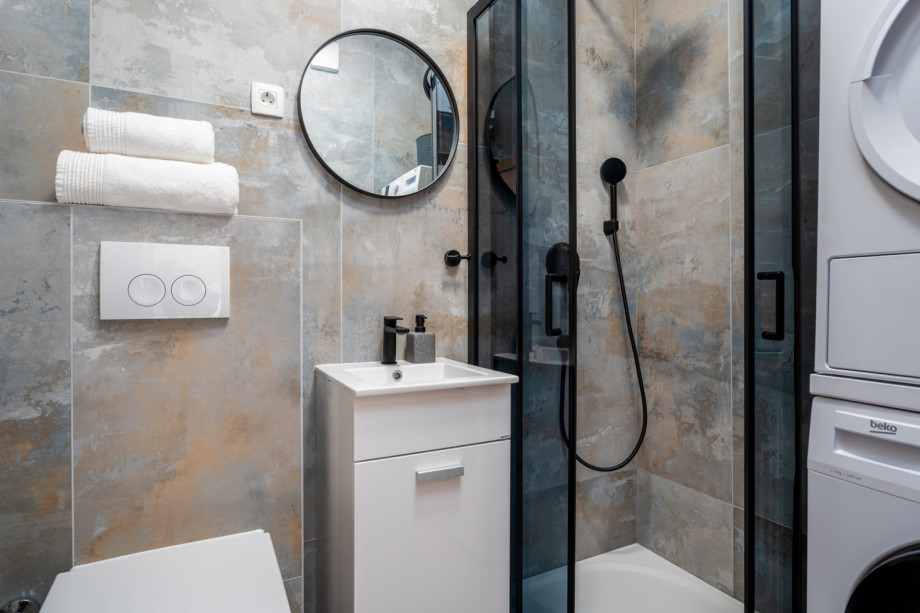 Bathroom with a shower, washing machine, and a dryer