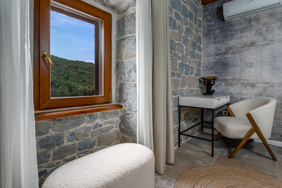 A stylish open-plan kitchen and living area with a window looking toward unspoiled nature.