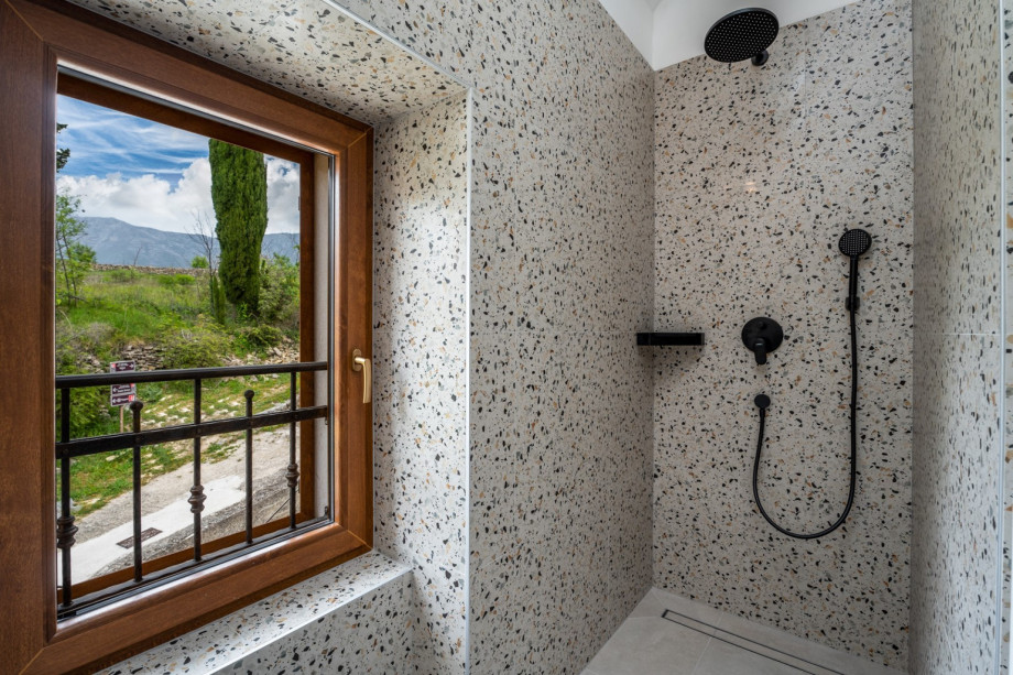 En-suite bathroom with a shower, and window looking toward nature surrounding