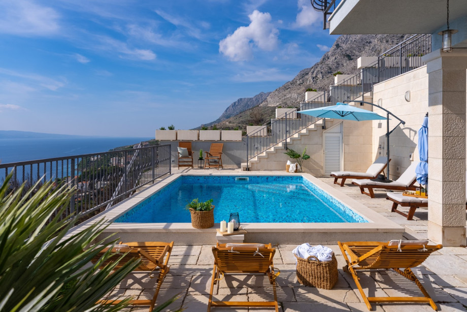The modern pool with crystal-clear water is nestled against the steep slope, offering a blend of luxury and mountain nature.