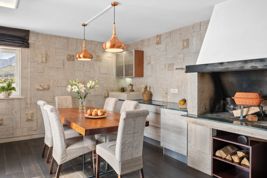The rustic dining area features a large table, copper pendant lighting, and a traditional indoor fireplace/grill, ideal for preparing Dalmatian specialities