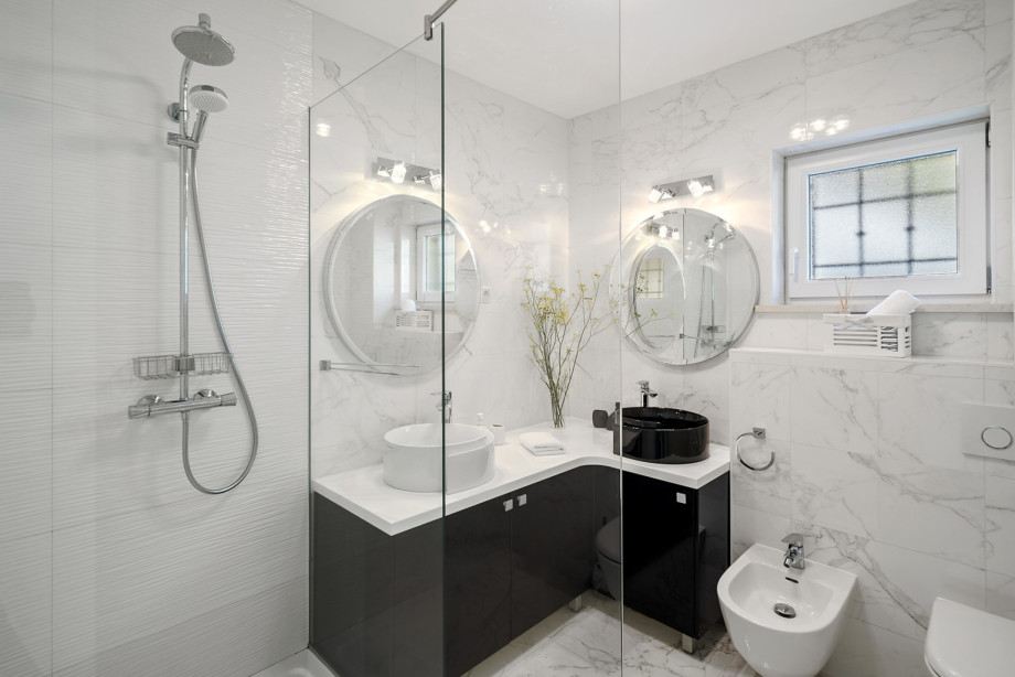 The ensuite bathroom features white marble tiling, contrasting black and white vessel sinks, and a spacious walk-in shower