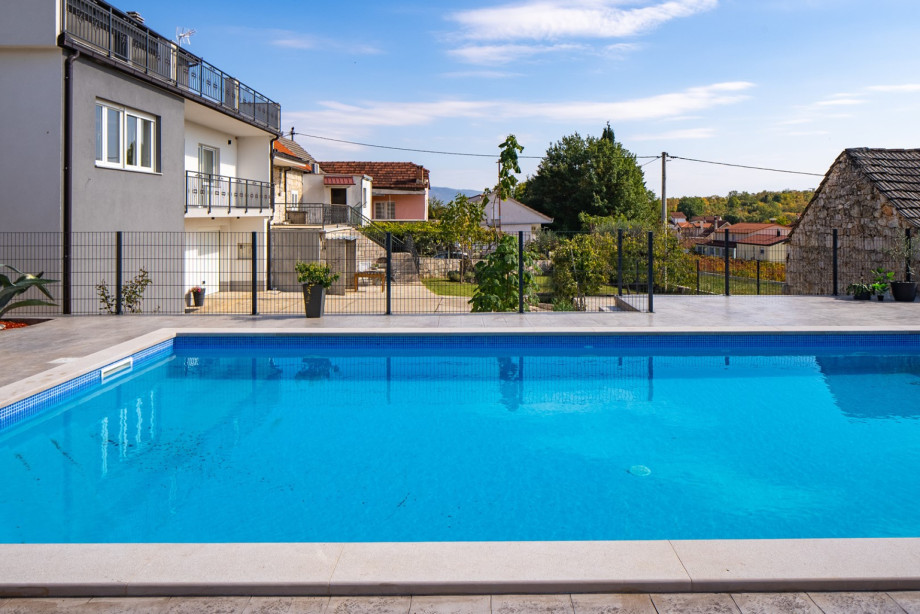 Der private Swimmingpool befindet sich zwischen den beiden Ebenen des Hauses und bietet einen erfrischenden Mittelpunkt für Entspannung im Freien.