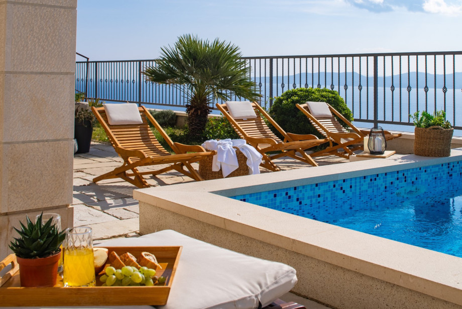 Wooden sun loungers by the pool are an ideal spot for sunbathing and enjoying a refreshing drink while overlooking the Adriatic Sea