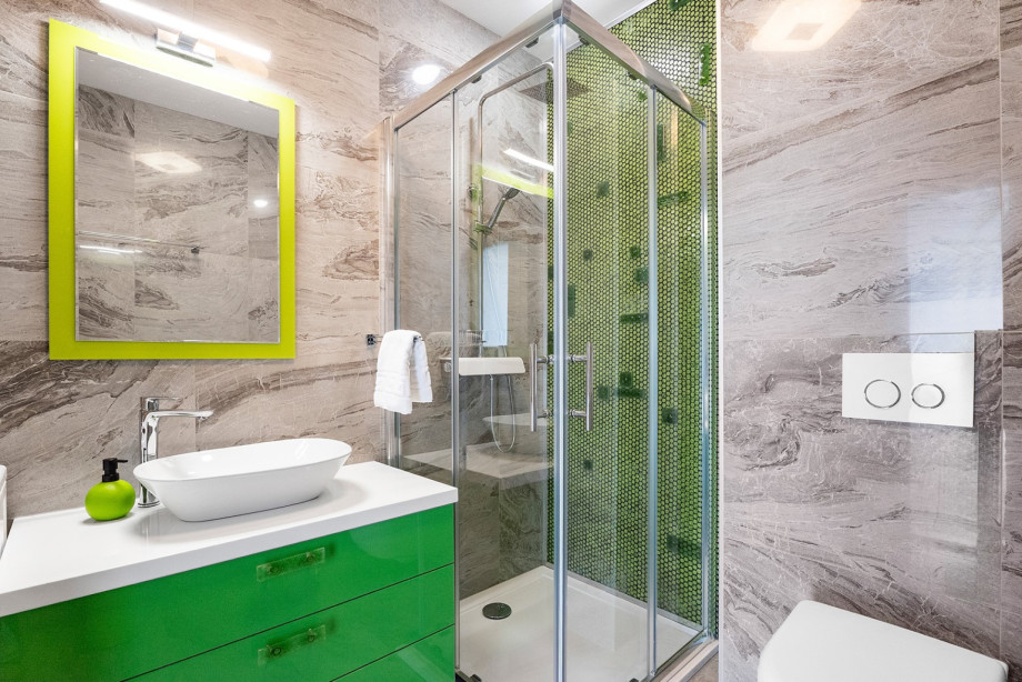 The family bathroom, located on the living area level, features a bright green vanity and a mosaic shower. There is also a washing machine