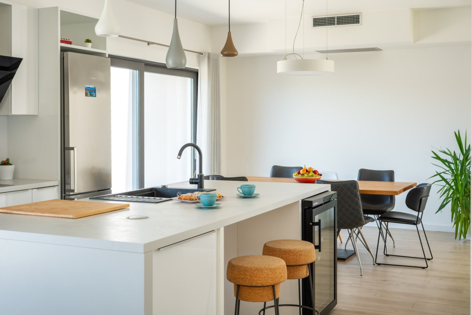 As you step inside, you are greeted by a seamless open-plan living, dining, and fully equipped kitchen area