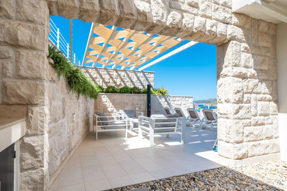 A covered dining area beckons guests to enjoy al fresco meals in style, complete with a summer kitchen