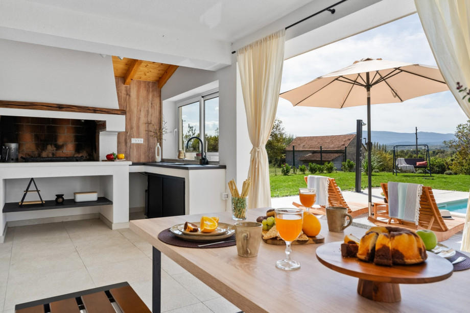 A covered dining area for six with a barbecue (wood-charcoal), a kitchen top with an electric cooktop, and a sink
