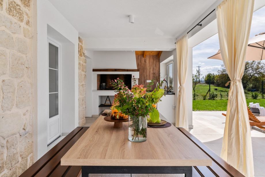 A covered dining area for six with a barbecue