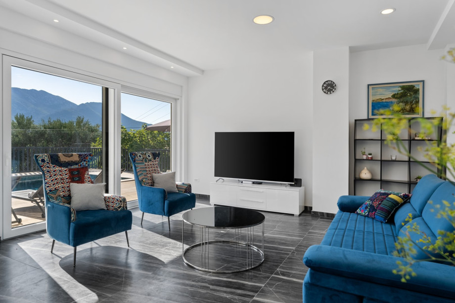 The interior features a large living/dining area with glass sliding doors on two sides that open to the outdoor pool area.