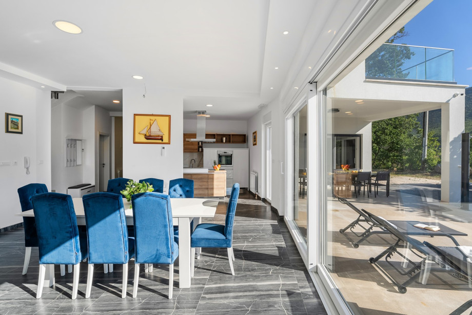The interior features a large living/dining area with glass sliding doors on two sides that open to the outdoor pool area.