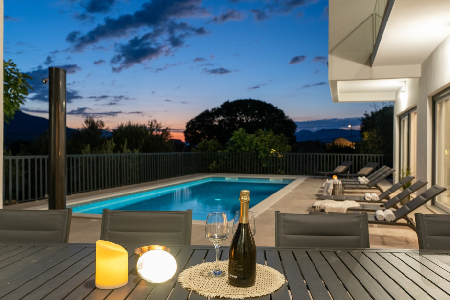 Covered dining area with enough seating for 10 people and a charcoal / wood barbecue