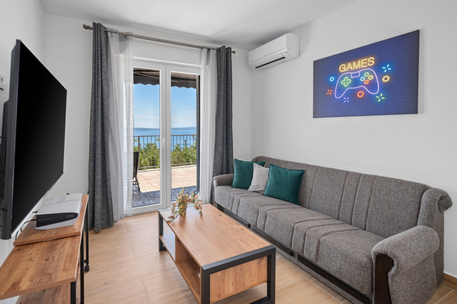 A media room featuring a cozy sofa that can be folded into a 110cm by 190cm sofa bed, air conditioning, free WiFi, a smart TV, a PS5 for your little one