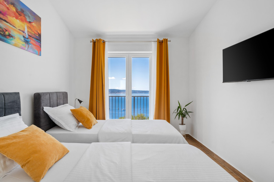 Third bedroom is 13 square meters and has two 90-by-200-cm single beds, a TV, air conditioning, a balcony, and views of the sea.