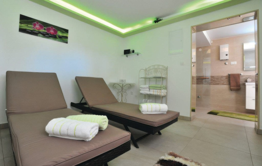 The serene spa zone features a relaxation room with two lounge chairs and mood lighting, perfect for unwinding after a swim.