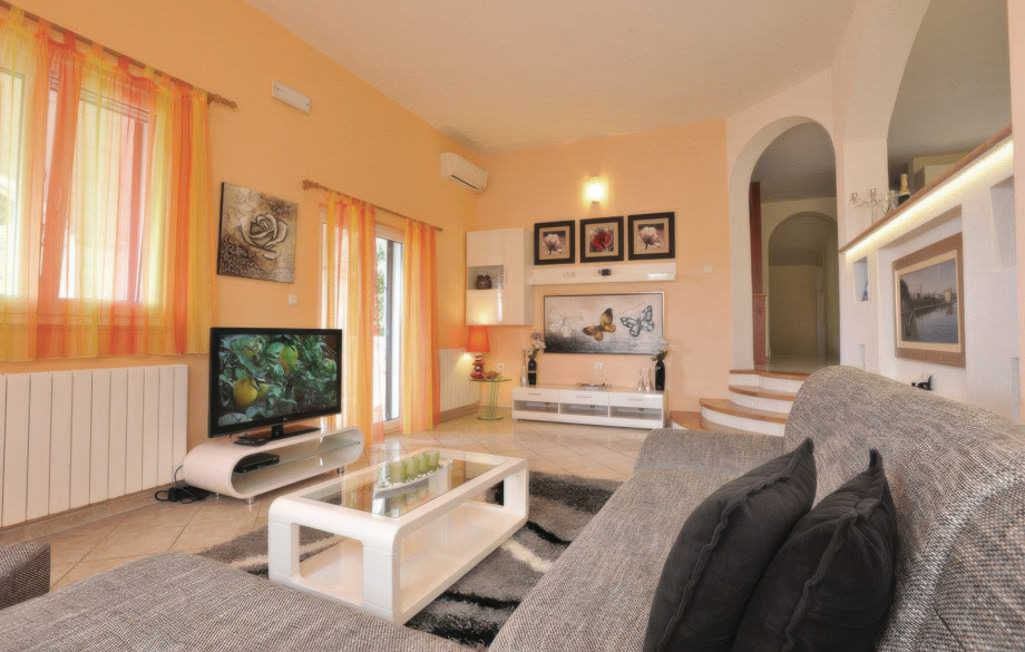 The bright, air-conditioned living area of the First Apartment features comfortable seating, a TV, and direct access to an outdoor space.