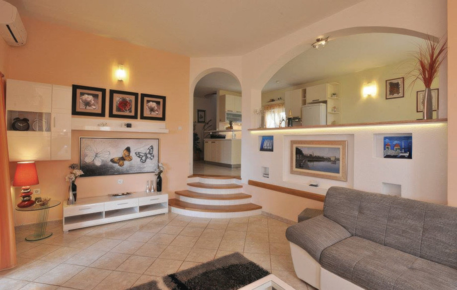 This view captures the open-plan design of one apartment, showing the transition from the living area to the fully equipped kitchen and dining space via archways and steps.