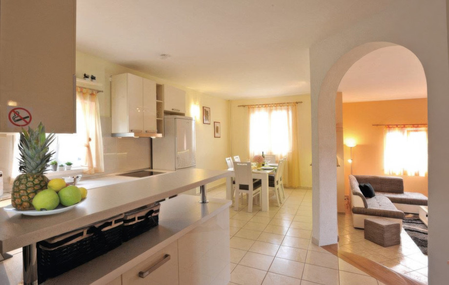 The kitchen and dining area of one apartment are bright and airy, opening up through an archway into the separate, adjacent living room.