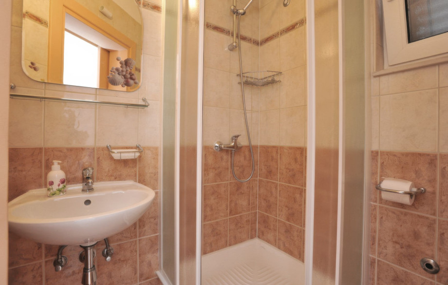 A family bathroom in one of the apartments features a tiled interior with a shower and basic amenities.