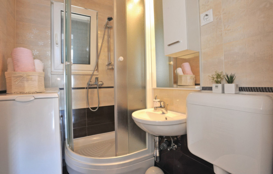 A well-maintained bathroom features a corner shower, a sink, and a convenient washing machine, adding to the villa's practical amenities.