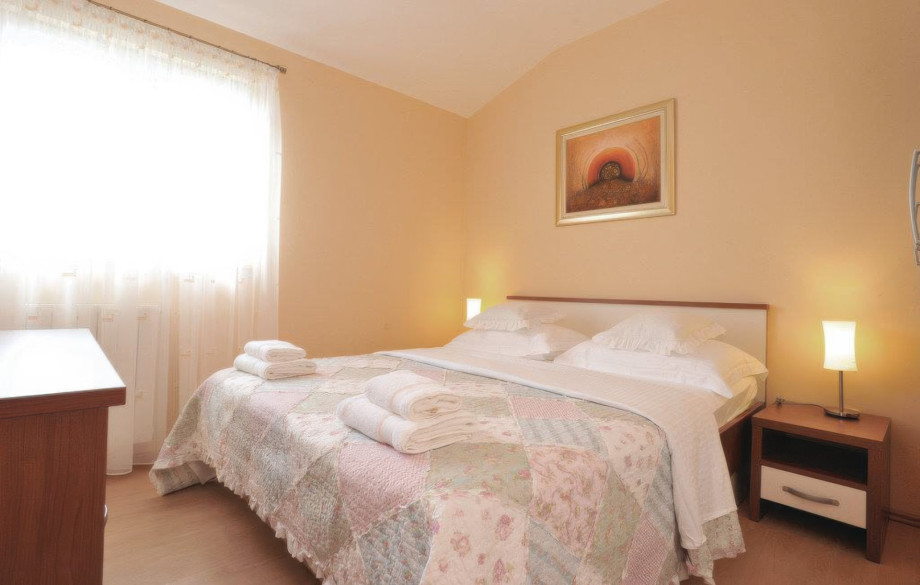 This bright and comfortable bedroom showcases a double bed with a patchwork quilt and bedside lamps, providing a welcoming atmosphere.