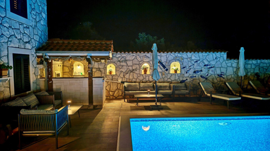 The poolside bar and lounge area are highlighted at night, offering a well-stocked and stylish spot for enjoying evening cocktails.