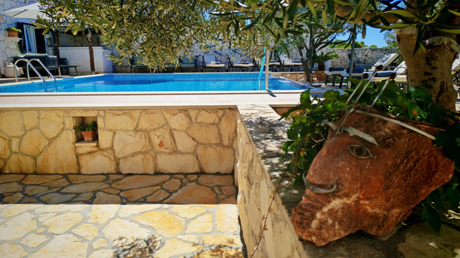 Charming stone paths and traditional decorative elements lead the way to the no-chlorine private swimming pool under the shade of olive trees.