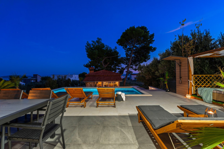 A poolside oasis with comfortable furniture, and a beautiful view