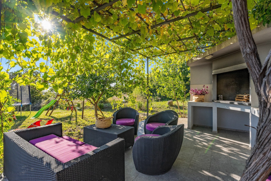 Comfortable lounge corner next to a traditional barbecue all with natural shade