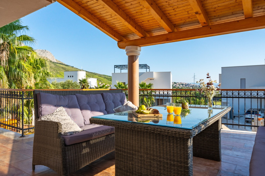 a spacious covered terrace with lounge corner and a TV with view on the pool and the sea