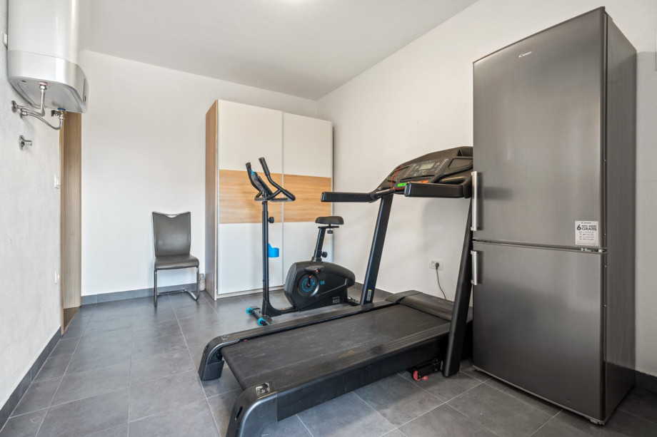 A door next to the living area is a gym with a Treadmill and Multi-Function machine, A/C