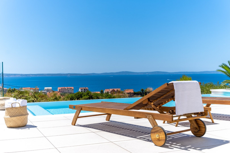 The sun deck area with 6 deck chairs with pillows, a sun umbrella, outdoor shower