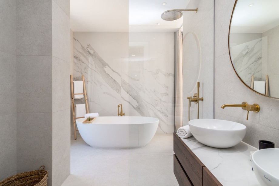 An en-suite bathroom with a bathtub, a shower, double-sink, and a toilet