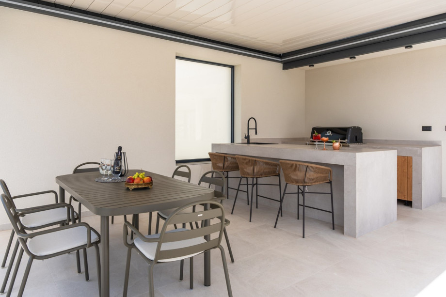 Covered dining area for 8 people, and a kitchenette with a gas barbecue