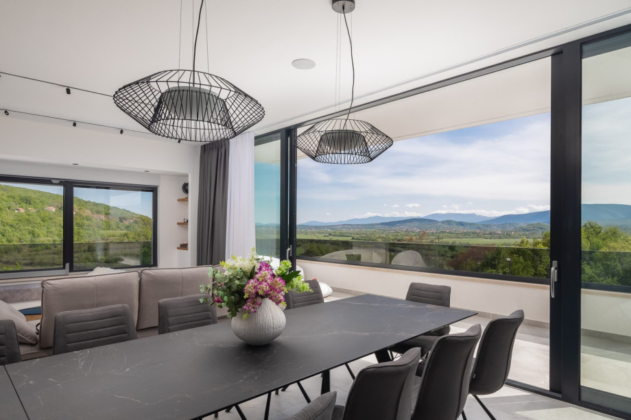 A spacious dining area, and a living room with a flat-screen TV and a balcony overviewing the valley and pool area