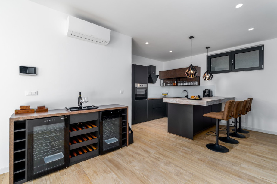 Fully equipped Kitchen with a kitchen island, a wine cooler, dining area with a table .