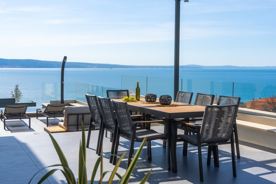 Covered outdoor dining table with barbecue and a lounge corner