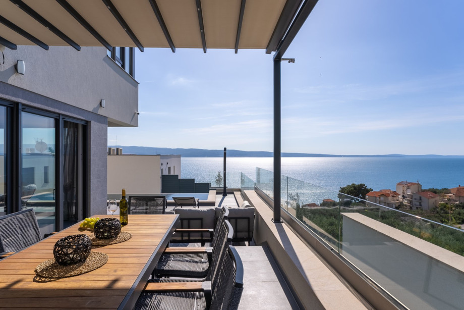 Covered outdoor dining table with barbecue and a lounge corner