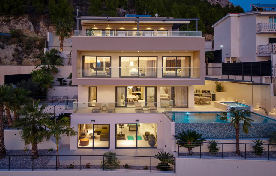 The exterior of the Luxurious 5-Bedroom Villa "Million Dreams" is organised over four levels, highlighting the pool and expansive glass doors.