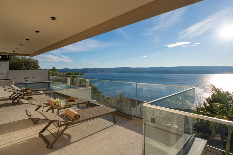 This terrace provides sun deck space with loungers and glass railings for uninterrupted, breathtaking sea views.
