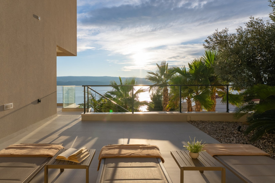 Sun loungers are set out on a lower-level terrace, providing a comfortable space to relax.