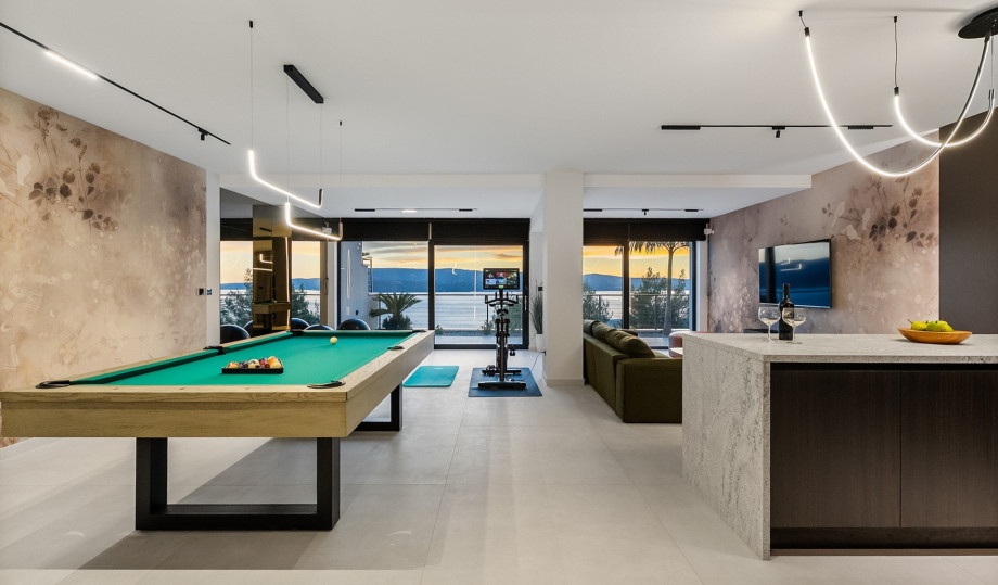The indoor entertainment zone on the spa level features a billiard table, a kitchenette, and an adjacent gym area