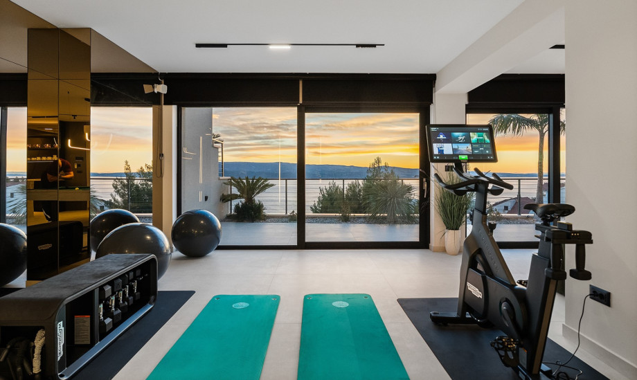 The fully equipped gym area includes an exercise bike, dumbbells, and pilates balls.